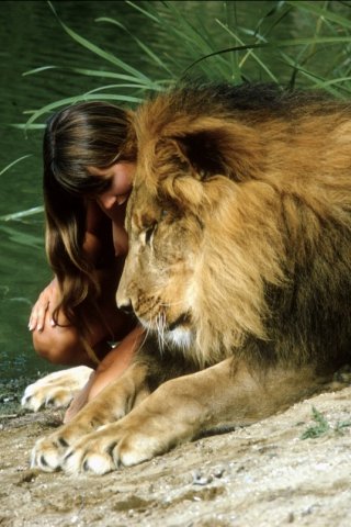 Обнаженная женщина обнимает льва на берегу реки